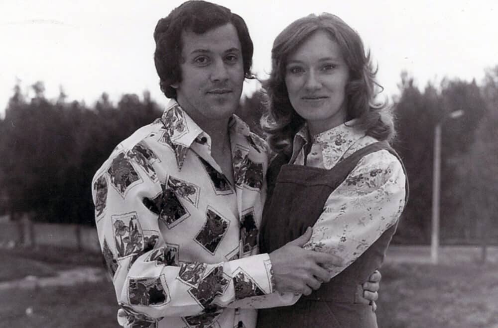 A man and woman stand, embracing each other in a black-and-white image.
