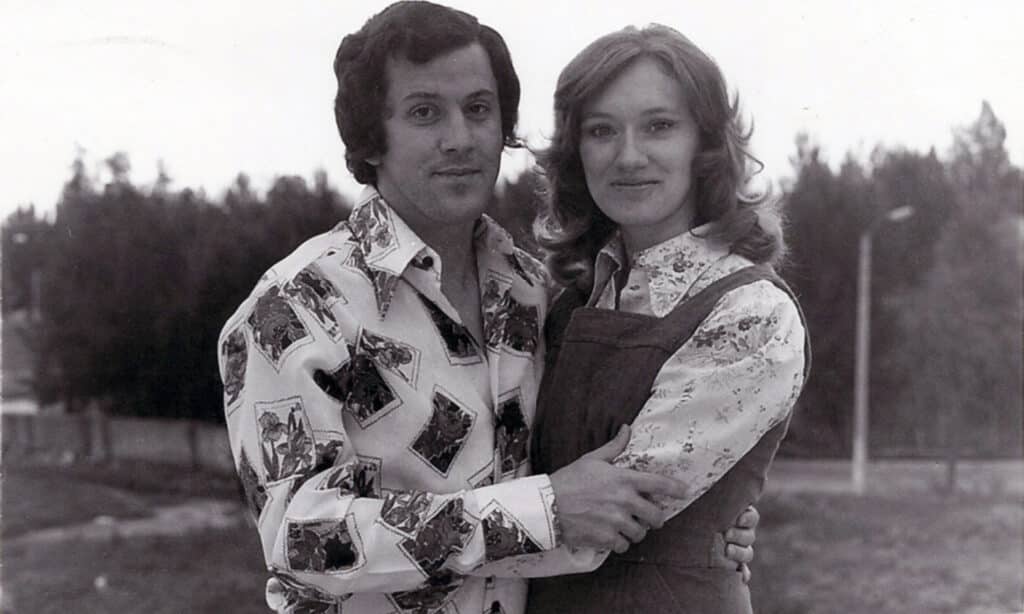 A man and women stand, embracing each other in a black-and-white image.
